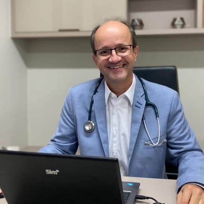 Dr. Allan Araujo, Cirurgião Geral e Digestivo, sorridente em seu consultório.